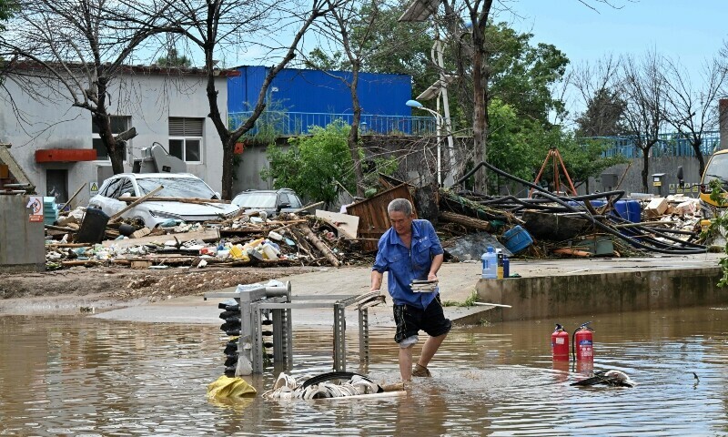 A man salvages items in a flooded area in Miyun district, northern Beijing on July 29. &mdash; AFP