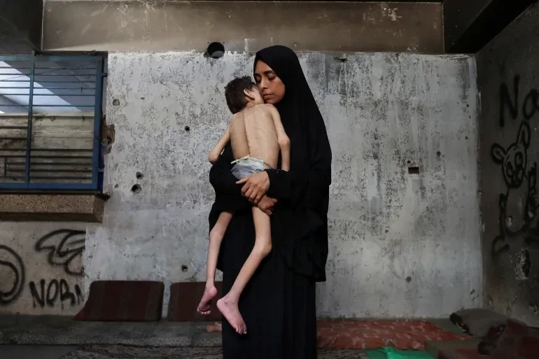 Displaced Palestinian mother Samah Matar holds her malnourished son Youssef, who suffers from cerebral palsy, at a school where they are sheltered. — Reuters