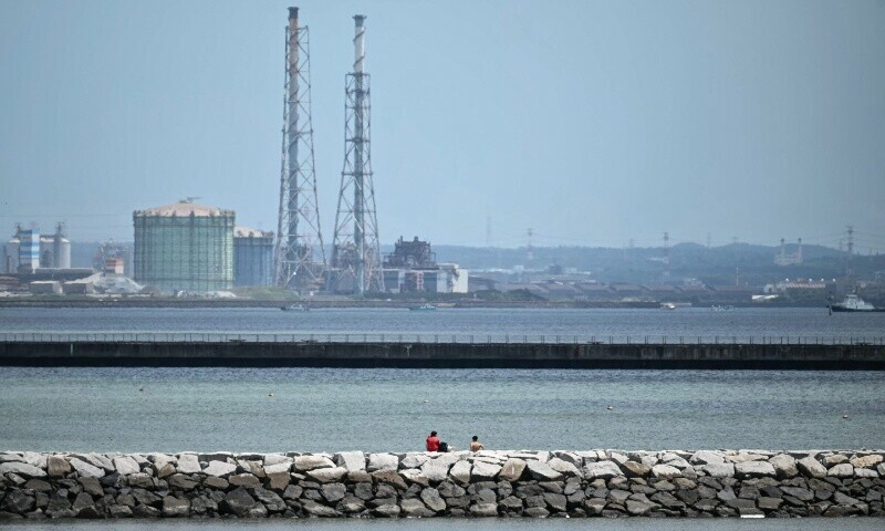 Two people (C) sit out on a breakwater after much of coastal Japan went on tsunami alert following a 8.8-magnitude quake in the sea off eastern Russia, along Tokyo Bay in Chiba City, Chiba prefecture on July 30, 2025. — AFP