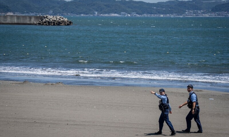 Police officers ask people to evacuate an empty beach due to a tsunami warning in Fujisawa city, Kanagawa prefecture on July 30. — AFP