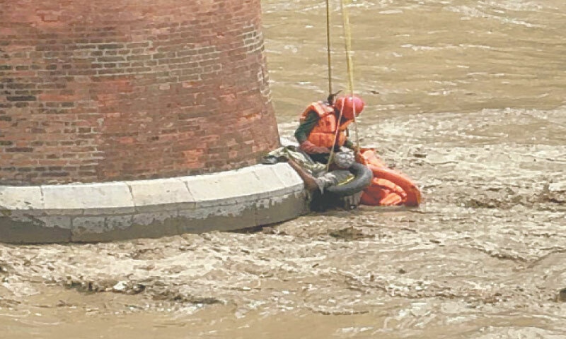 Rescuers save a man trapped in floodwaters in Haro River in Attock on Wednesday. &mdash; Dawn