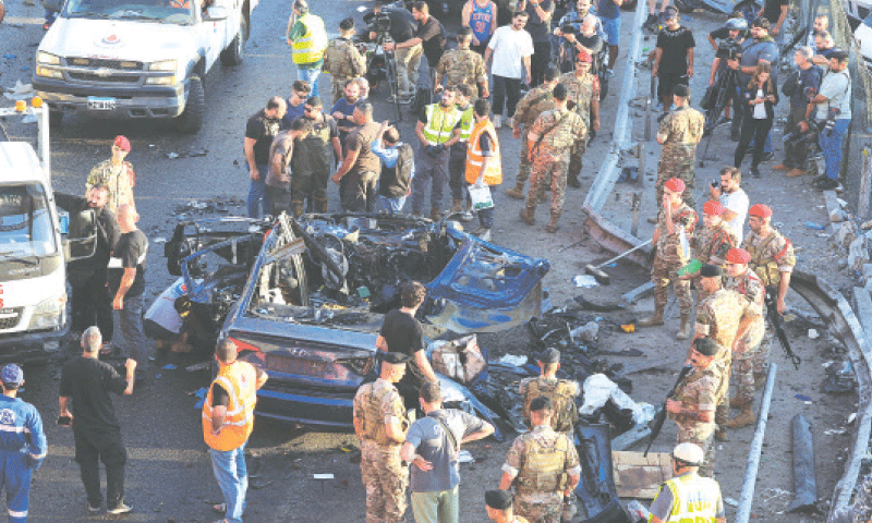 Members of the Lebanese army and people gather near a damaged car after an Israeli strike in Khaldeh on Thursday.—Reuters
