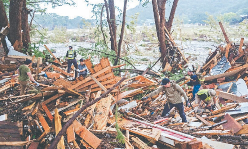 RESCUE workers dig through debris as they look for people swept up in flash floods in Hunt, Texas.—AFP