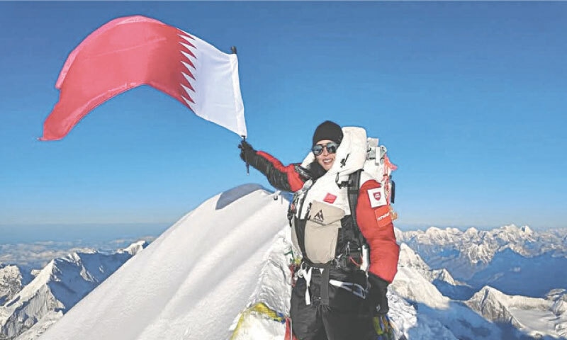 SHEIKHA Asma Al Thani raises her country’s flag atop Nanga Parbat.—Dawn