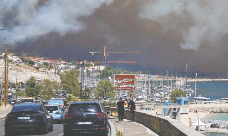 PEOPLE living on the outskirts of Marseille watch as smoke from a wildfire rages in the background.—AFP