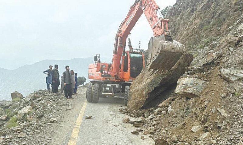 A machine removes the debris after a landslide blocked Khar-Barang Road in Bajaur on Wednesday. — Photo by Anwarullah Khan