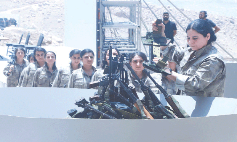Fighters belonging to the Kurdistan Workers Party line up to put their weapons into a pit during a ceremony at Sulaimaniyah, in Iraq’s Kurdistan region, on Friday. —AFP