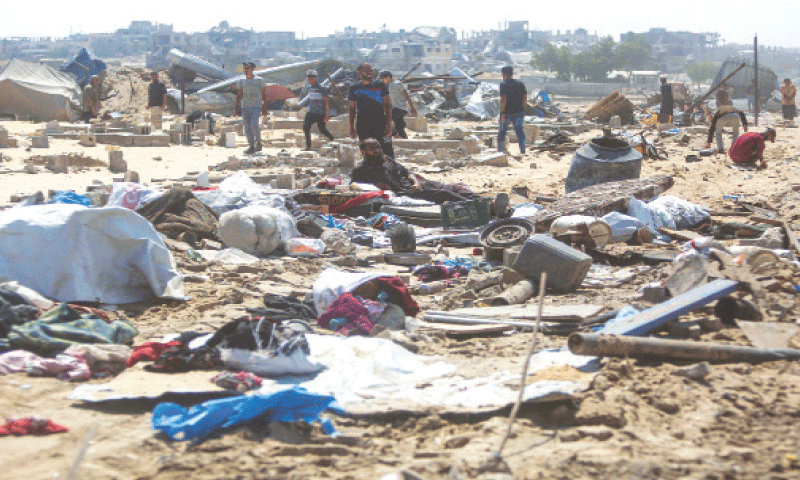 KHAN YUNIS: Palestinians inspect the destruction at a makeshift camp following an incursion by Israeli tanks.—AFP
