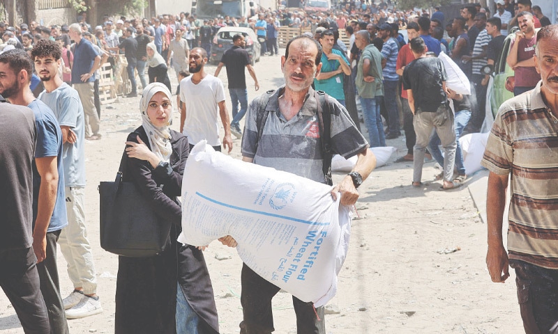 A Palestinian man carries a bag of flour at a warehouse of UN World Food Programme on Al-Jalaa street in central Gaza Strip on Saturday.&mdash;AFP