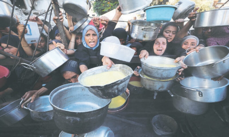 Palestinian women in a crushing queue cry out for food at a Gaza charity kitchen.—Reuters