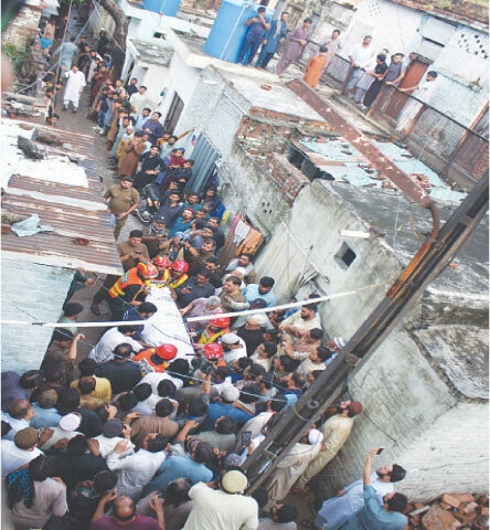 LAHORE: Rescue workers move the body of a person killed after the roof of a house collapsed due to heavy rainfall in the Railway Colony area.—PPI