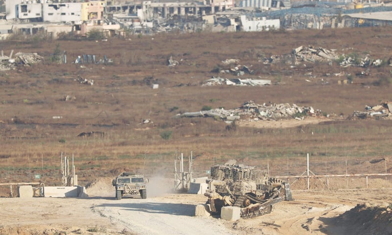 This picture taken from Israel’s border with the Gaza Strip shows Israeli troops and an army bulldozer near the separation fence on Thursday. — AFP
