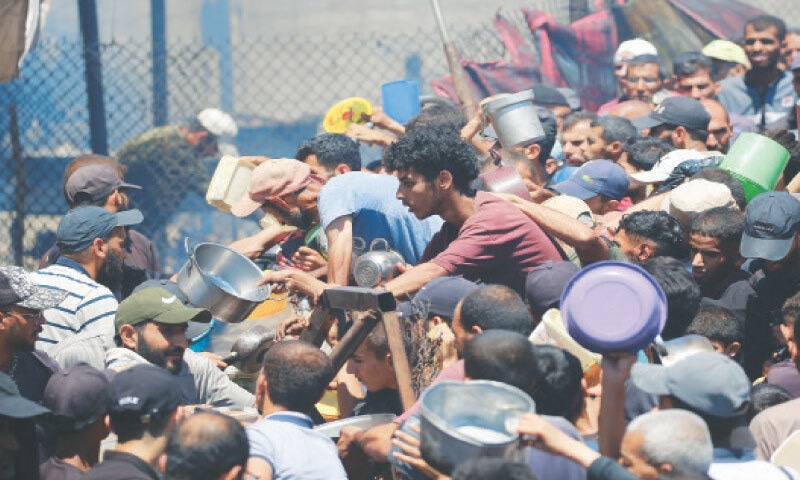Palestinians gather at a food distribution point in the Nuseirat refugee camp in central Gaza Strip on Saturday.—AFP