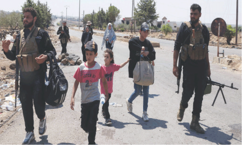 A family is being escorted by Syrian security officials out of Sweida on Monday.&mdash;AFP
