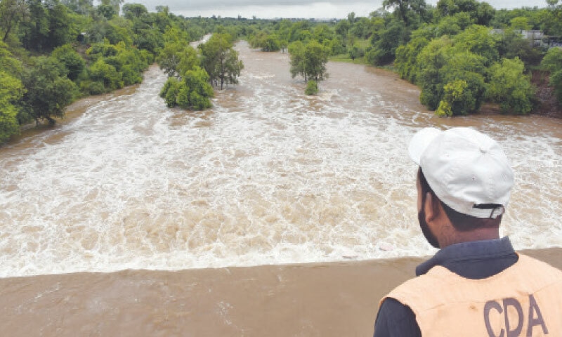  A CDA official stands at a bridge on Park Road to keep an eye on picnickers and fishermen as the district administration has imposed Section 144. The administration opens Rawal Dam spillways for third time this week on Tuesday. &mdash; Photo by Tanveer Shahzad 