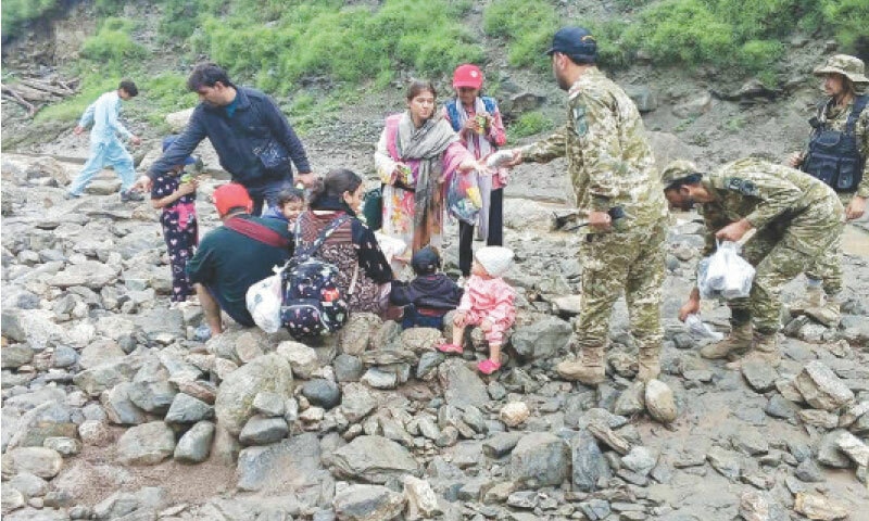 BABUSAR: Soldiers help tourists who became stranded after landslides, triggered by torrential monsoon rains, blocked roads and swept away several vehicles.&mdash;AFP