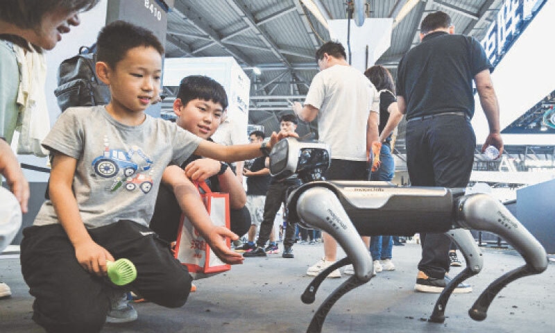 CHILDREN interact with Magic Dog, a quadruped robot, during the World Artificial Intelligence Conference at the Shanghai World Expo.—AFP