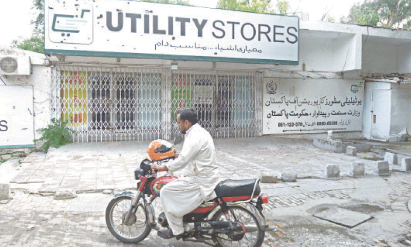 A motorcyclist rides past a closed outlet of Utility Stores Corporation in G-6 area of Islamabad on Thursday. — Photo by Mohammad Asim