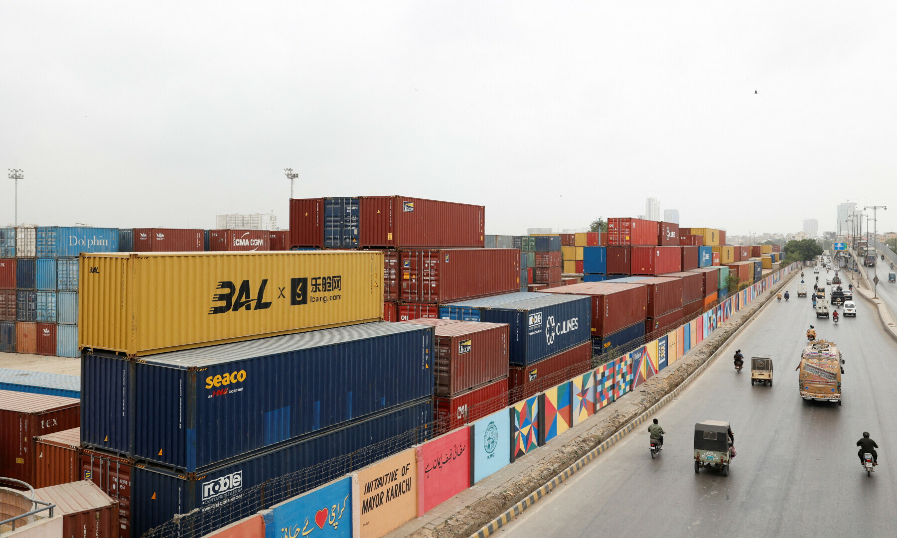 Vehicles move past a warehouse yard with shipping containers near port area in Karachi on July 31, 2025. — Reuters/Akhtar Soomro