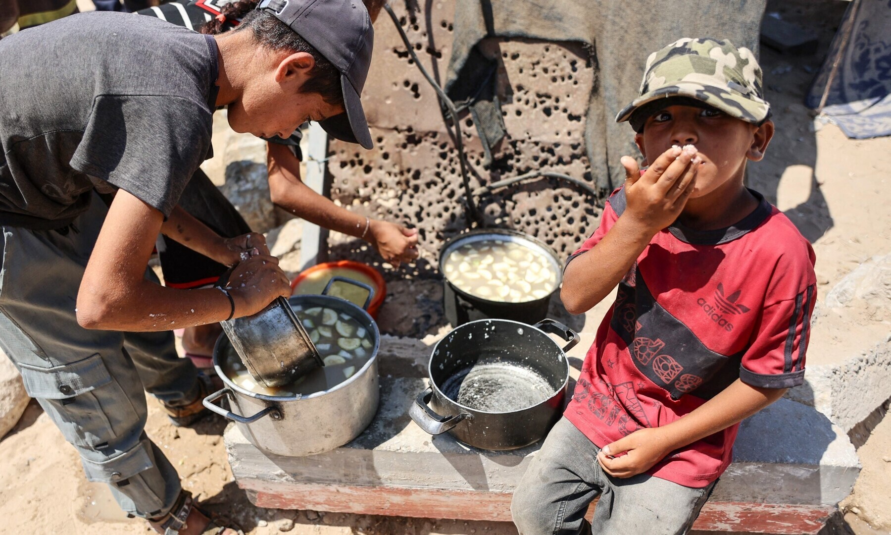  Palestinian children eat their meal from cooking pans in Gaza City on August 1, 2025. &mdash; Photo by Omar Al-Qattaa / AFP 