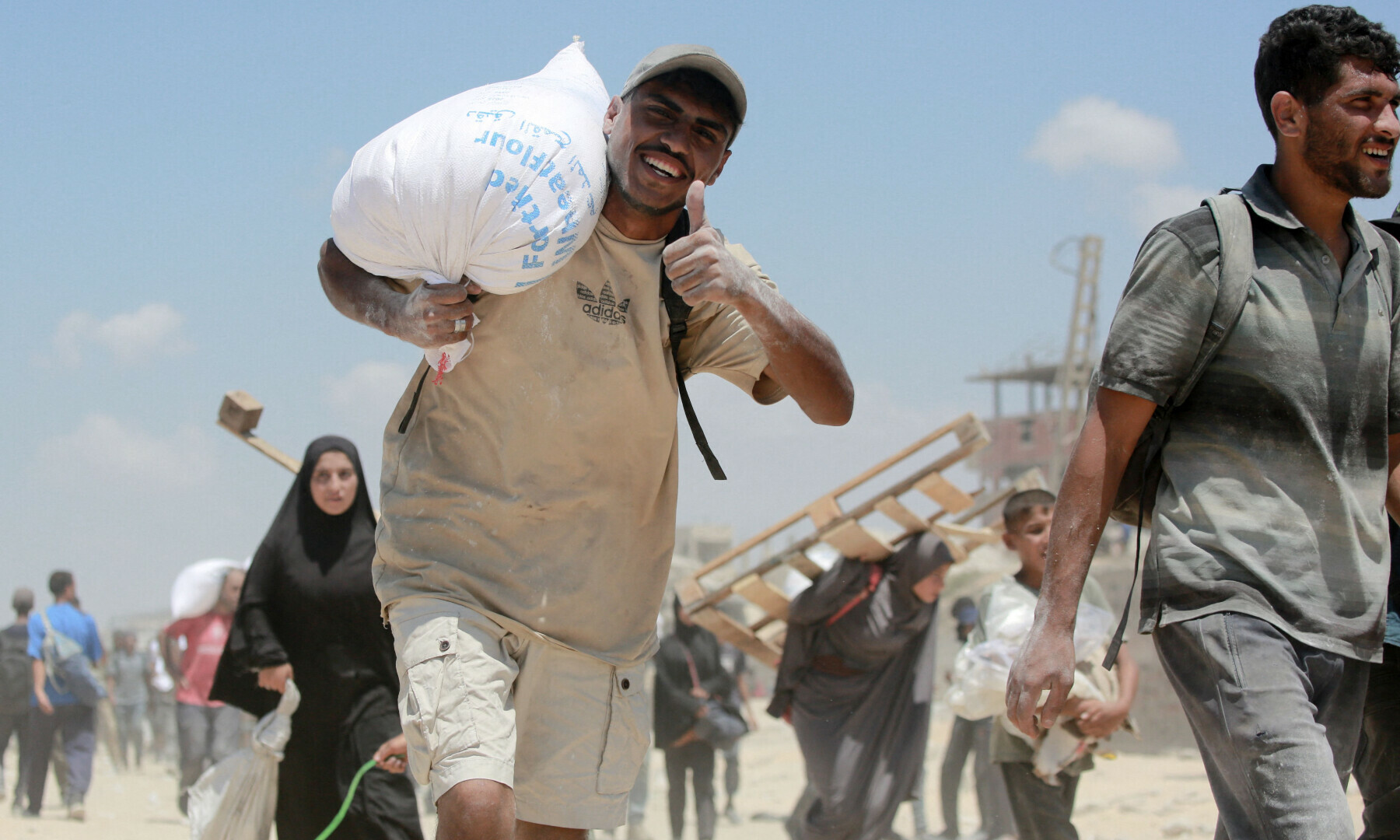  A Palestinian man smiles as he carries a bag of flour that he obtained from aid trucks which entered Gaza through the Zikim crossing point, in Jabalia in the northern Gaza Strip on Aug 1, 2025. &mdash; AFP 