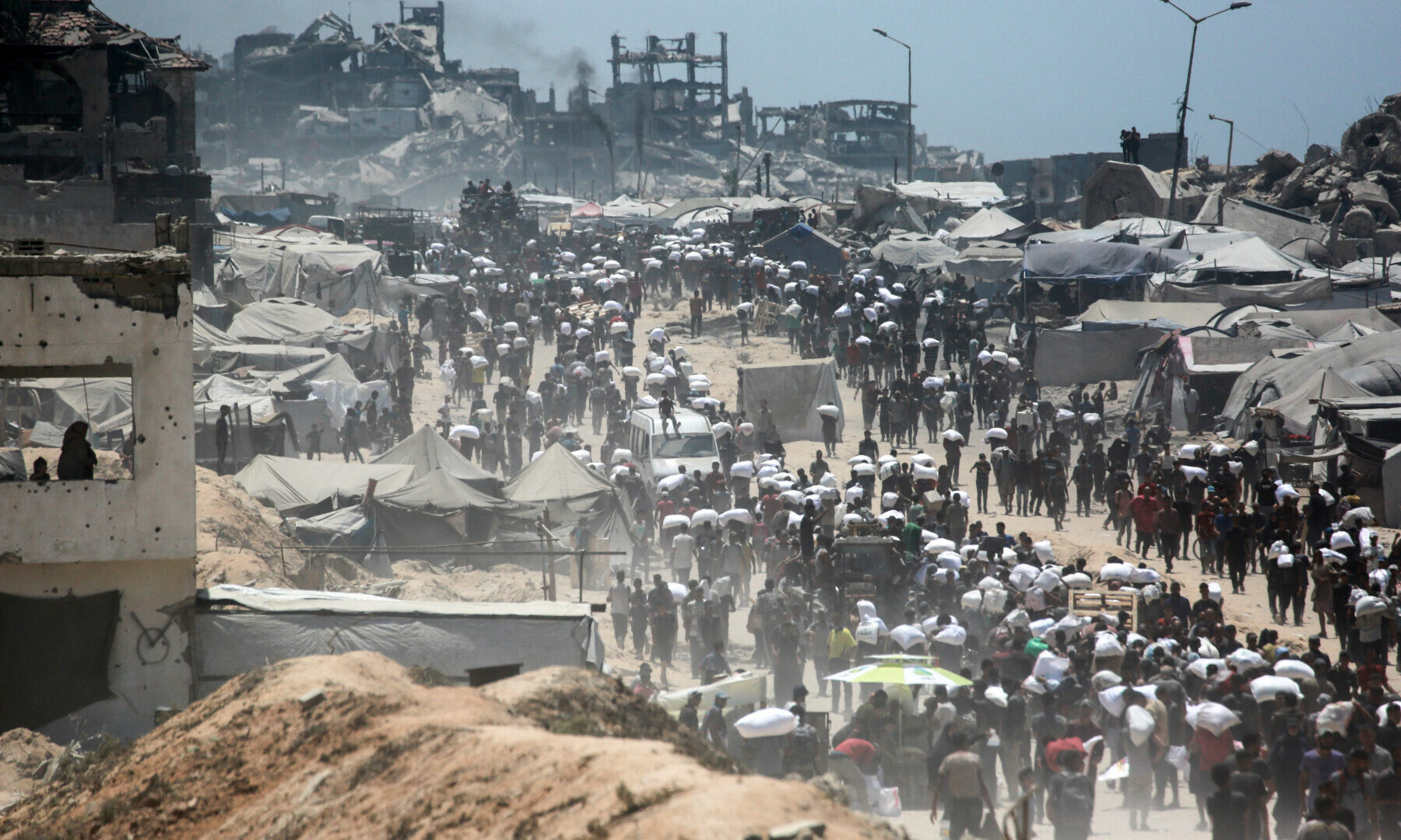  Palestinians carry bags of flour that they obtained from aid trucks which entered Gaza through the Zikim crossing point, in Jabalia in the northern Gaza Strip on Aug 1, 2025. &mdash; AFP 
