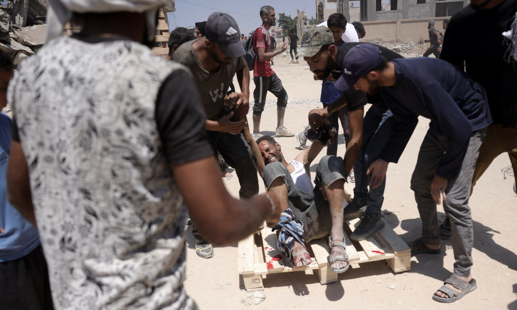  A Palestinian man is helped onto a wooden pallet after he returned injured from an area in which aid trucks entered Gaza through the Zikim crossing point, in Jabalia in the northern Gaza Strip on Aug 1, 2025. &mdash; AFP 
