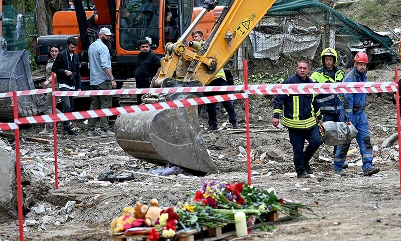 Rescuers carry a fragment of a Russian cruise missile outside a residential building in Kyiv, Ukraine on August 1, which was partially destroyed following a Russian missile strike on July 31. — AFP