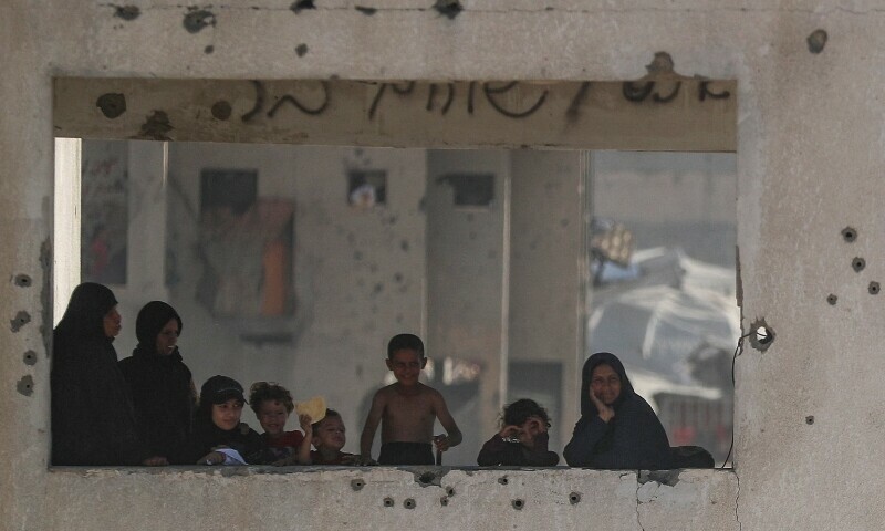 Women and children look out from a damaged building as Palestinians carry aid supplies that entered Gaza through Israel, in Beit Lahia, northern Gaza Strip, August 2. &mdash; Reuters