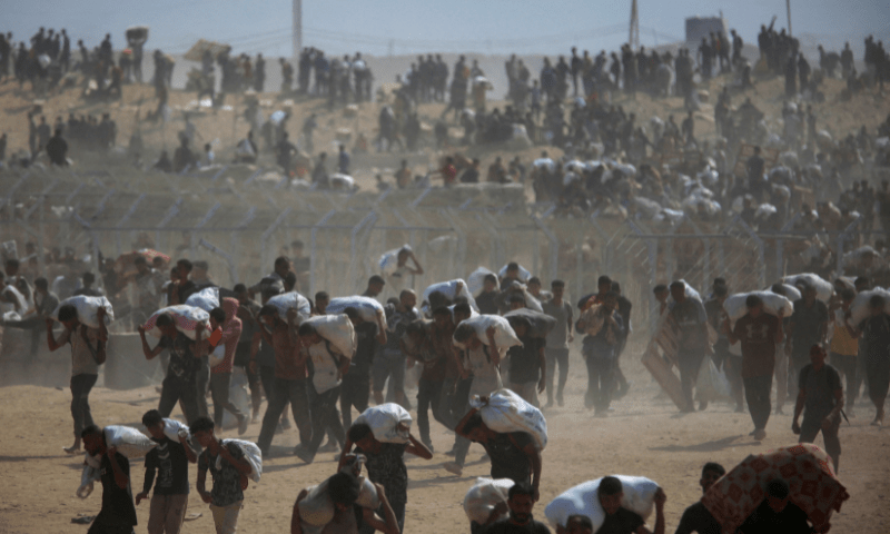  Palestinians carry aid supplies which they received from the US-backed Gaza Humanitarian Foundation (GHF), in the central Gaza Strip on August 4, 2025. &mdash; Reuters 