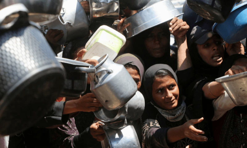  Palestinians wait to receive food from a charity kitchen, amid a hunger crisis, in Khan Younis, southern Gaza Strip on August 4, 2025. &mdash; Reuters 