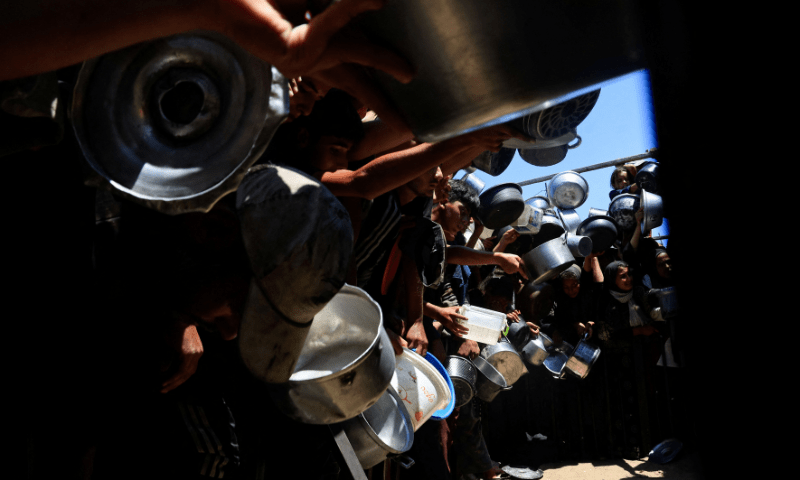  Palestinians wait to receive food from a charity kitchen, amid a hunger crisis, in Khan Younis, southern Gaza Strip on August 4, 2025. &mdash; Reuters 
