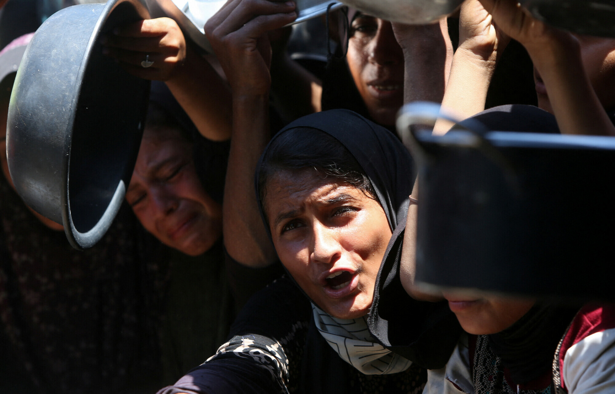  Palestinians wait to receive food from a charity kitchen, amid a hunger crisis, in Khan Younis, southern Gaza Strip on August 4, 2025. &mdash; Reuters 