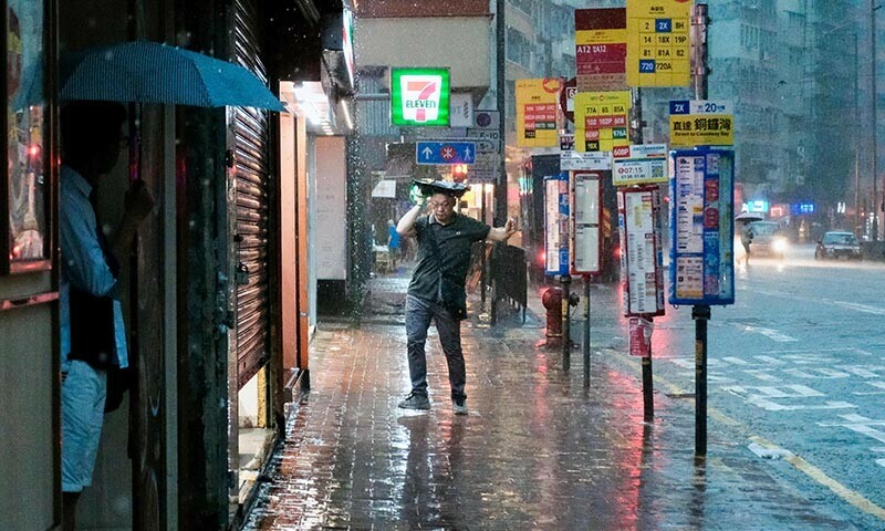 A pedestrian holds a bag over his head beside a bus stop in the Quarry Bay area of Hong Kong on Aug 5, 2025, amid a black rainstorm warning issued by the city&rsquo;s weather observatory. &mdash; AFP