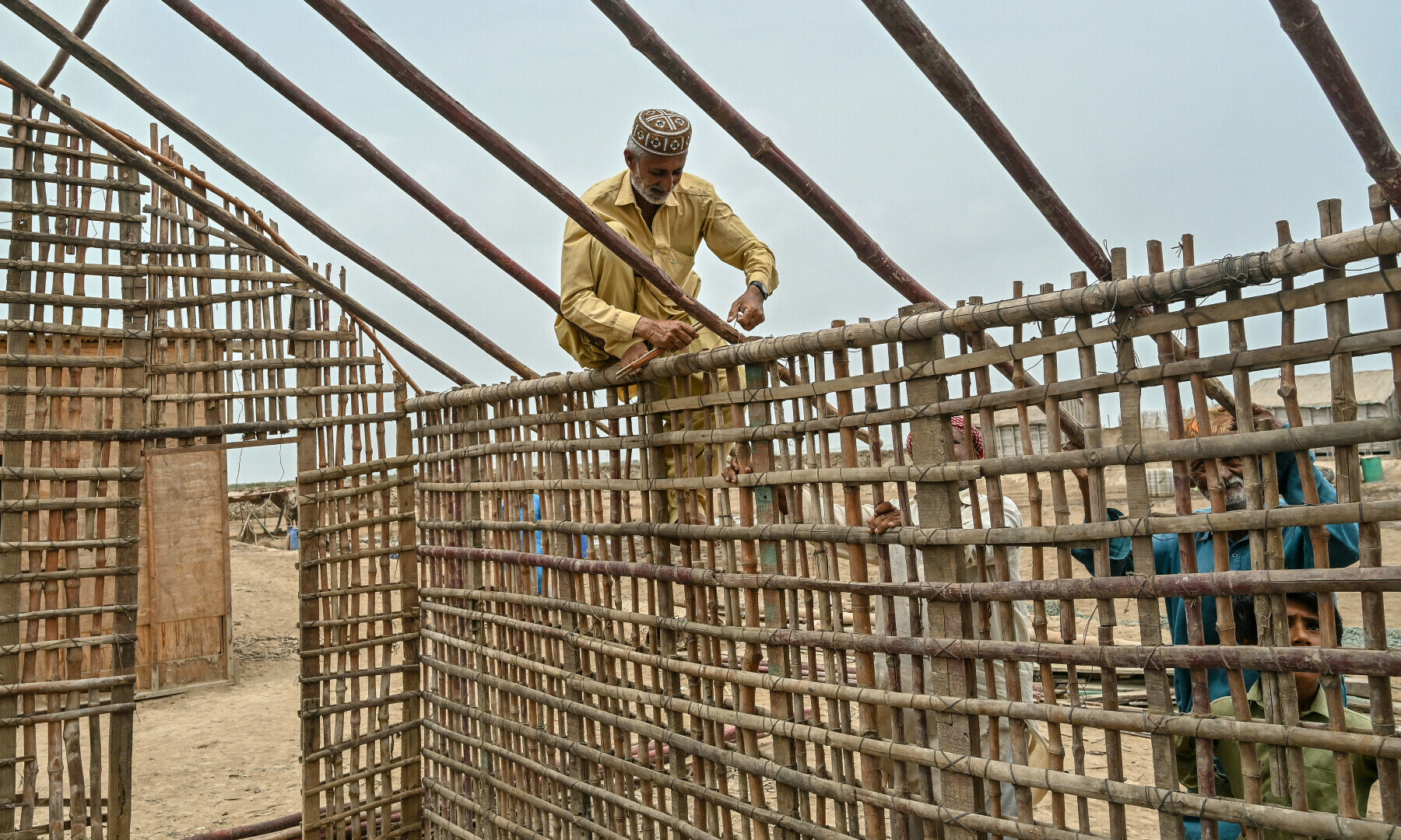 Haji Karam Jat, a fisherman, uses bamboo sticks to build his new house in Keti Bandar town of Thatta district near the Indus delta on June 25. — AFP