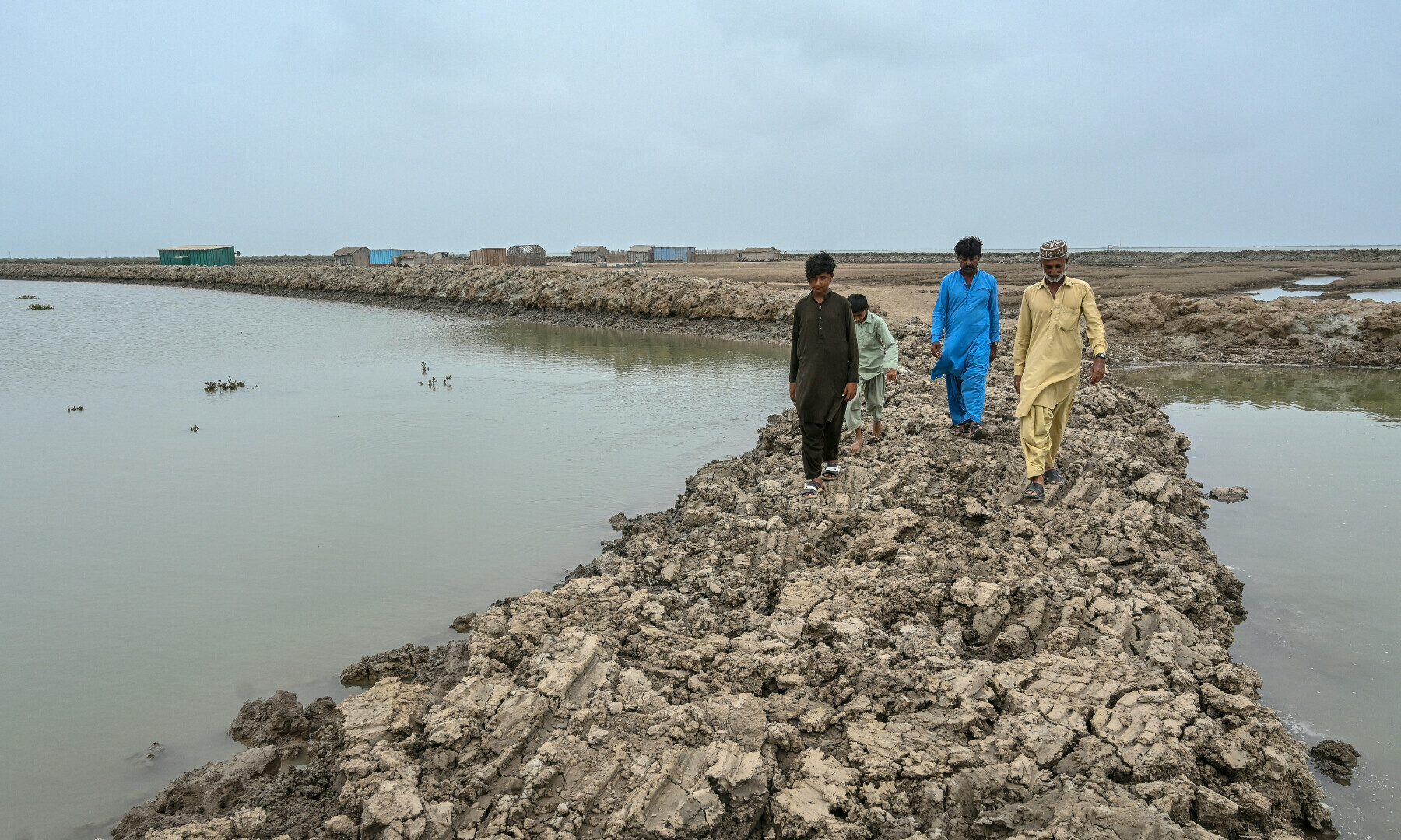 Haji Karam Jat (R), a fisherman, and his family members walk along an embankment in Keti Bandar town of Thatta district near the Indus delta on June 25. — AFP