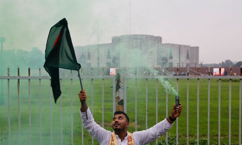 A man holds a Bangladeshi flag and a smoke flare during celebrations marking the one-year anniversary of student-led protests that led to the ousting of Bangladeshi then-Prime-Minister Sheikh Hasina, at Manik Mia Avenue, outside the parliament building, in Dhaka, Bangladesh, August 5. &mdash; Reuters
