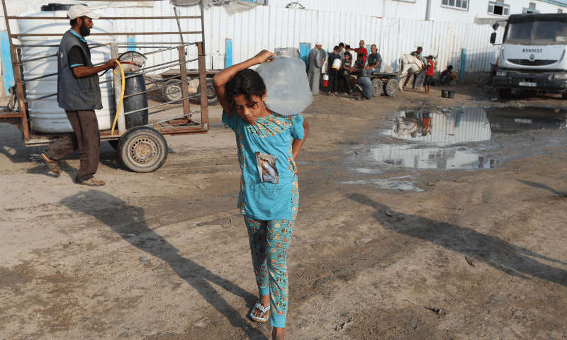 A Palestinian girl carries a container of water amid shortages, at a distribution point in Deir al-Balah in the central Gaza Strip on August 5, 2025. — Reuters