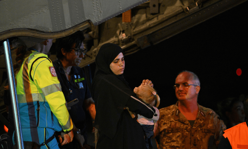  A woman carries a child as medics and health personnel welcome Palestinian children from Gaza and their families, after an Italian military plane C130J from Israel landed on August 14, 2025, at Rome&rsquo;s Ciampino airport. &mdash; AFP 