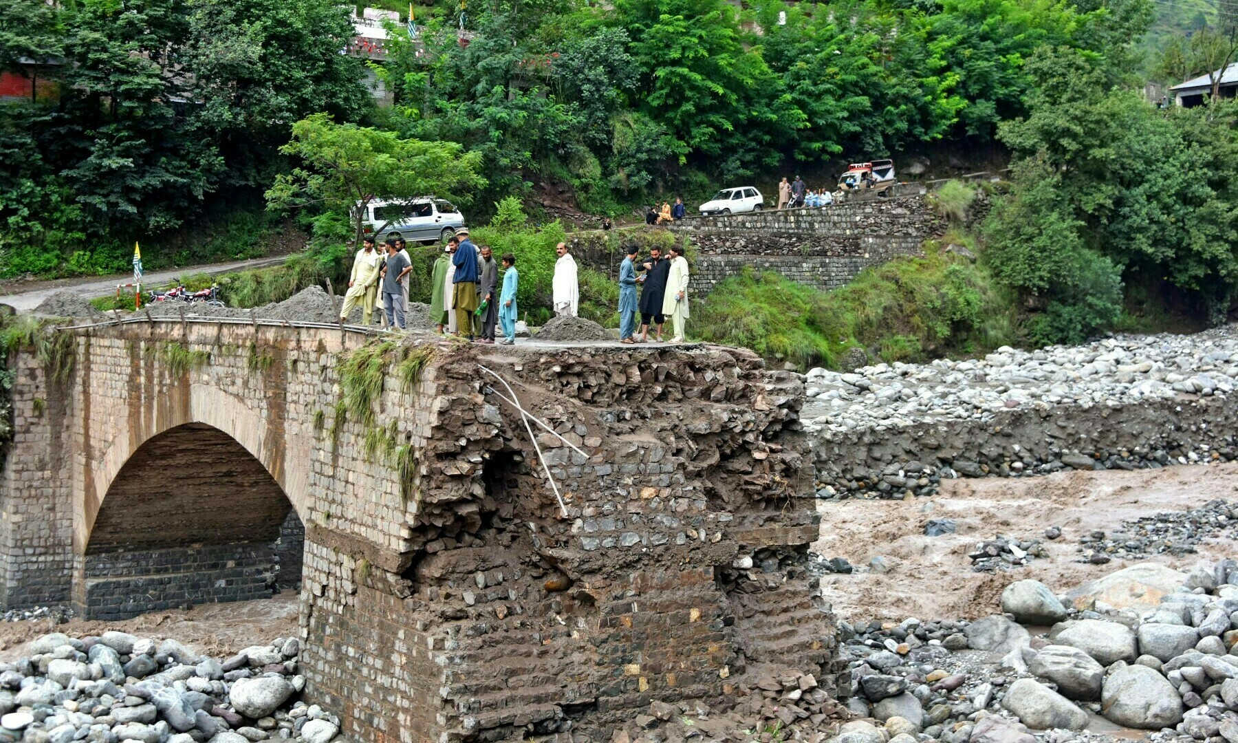  Onlookers gather near a destroyed bridge after flash floods on the outskirts of Muzaffarabad on August 15, 2025. &mdash; AFP 