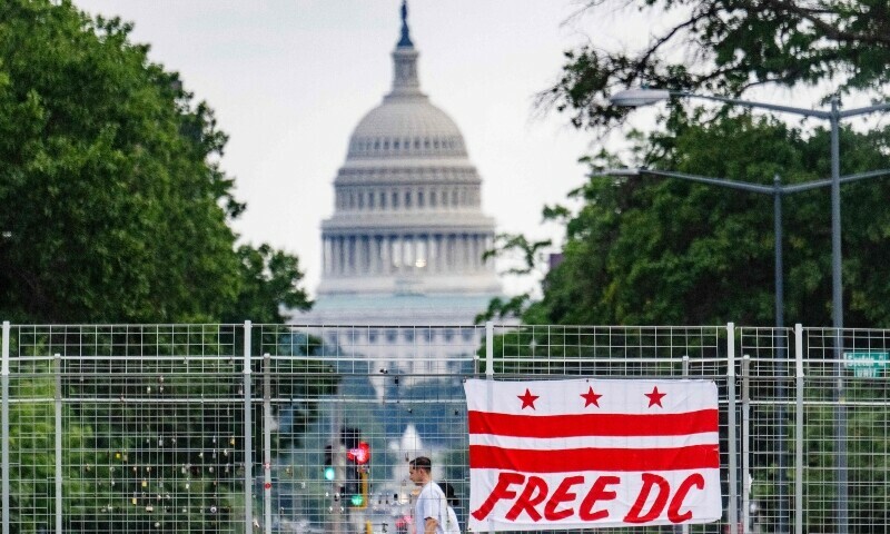 Pedestrians walk past a flag that reads &ldquo;Free DC&rdquo; hanging on an overpass near the US Capitol building in Washington, DC, August 15. &mdash; AFP