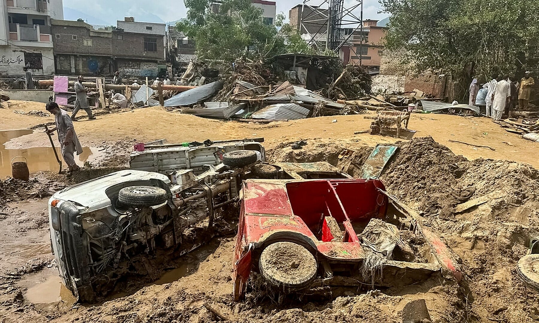 سوات کے علاقے مینگورہ میں لوگ تباہ شدہ گاڑیوں اور  ملبے کے پاس سے گزر رہے ہیں &mdash; اے ایف پی