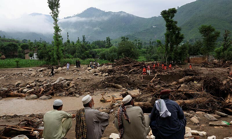 Residents sit as members of the Urban Search and Rescue team search for bodies amid debris of damaged houses following a storm that caused heavy rains and flooding, in Bayshonai Kalay, Buner district, Khyber Pakhtunkhwa on August 17. — Reuters