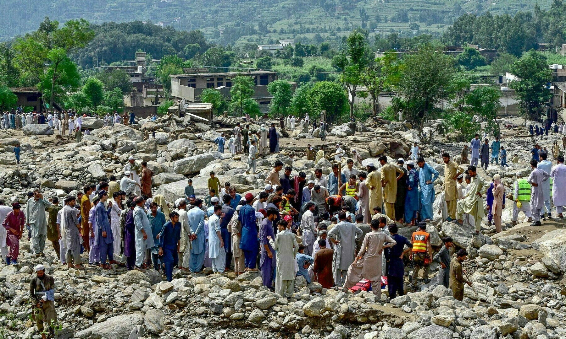 16 اگست 2025ء کو مون سون سے متاثرہ ضلع بونیر میں سیلاب کے ایک دن بعد ریسکیو اہلکار اپنے گھروں کے سامنے سے پتھر ہٹا رہے ہیں — تصویر: اے ایف پی