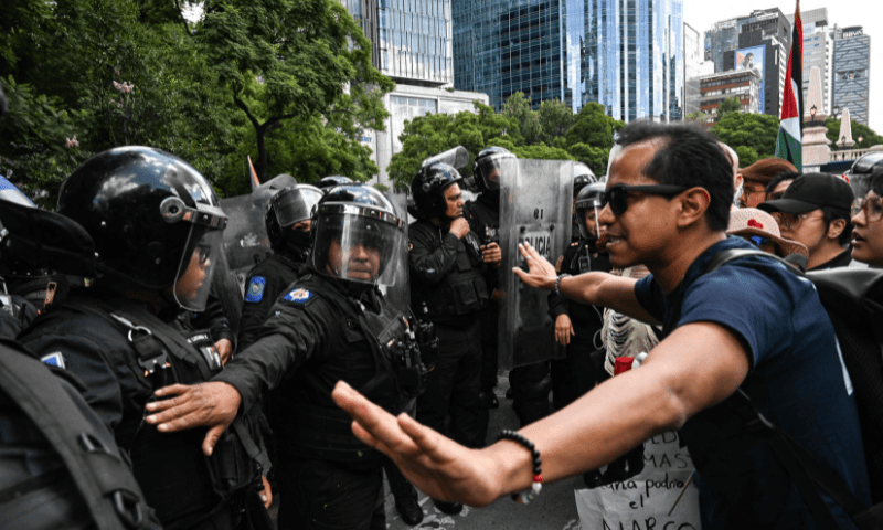  Riot police officers stand guard next to members of the Global Movement for Palestine during a rally against Israel&rsquo;s actions and the ongoing food shortages in the Gaza strip, in Mexico City on August 17, 2025. &mdash; AFP 