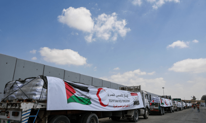  People walk past trucks loaded with aid for Gaza, waiting on the Egyptian side of the Rafah crossing in Rafah on August 18, 2025. &mdash; AFP 