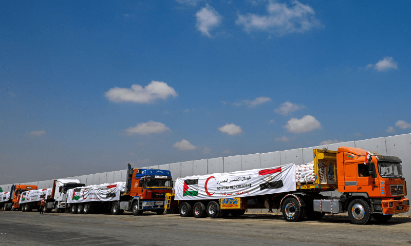  A man (L) walks past trucks loaded with aid for Gaza, waiting on the Egyptian side of the Rafah crossing in Rafah on August 18, 2025. &mdash; AFP 