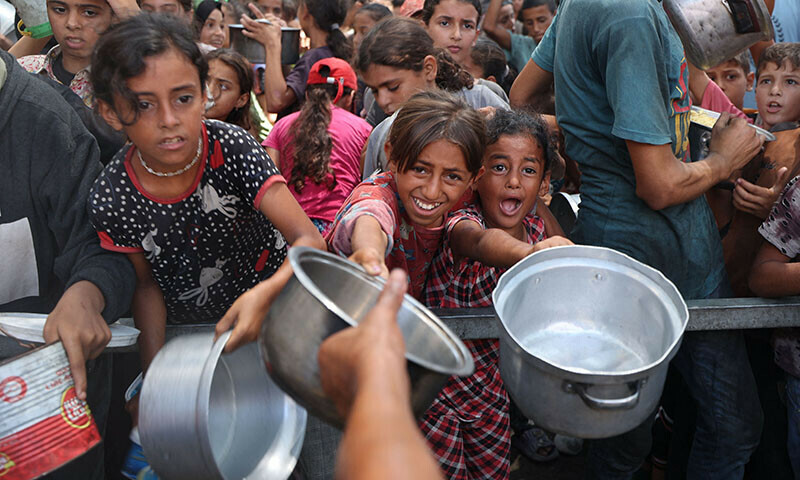 Palestinians gather to receive cooked meals from a food distribution centre in the Nuseirat refugee camp in the central Gaza Strip on August 18. — AFP