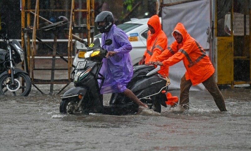 Civic authority workers help a stranded motorist on a flooded street during heavy rain showers in Mumbai on August 19. &mdash; AFP