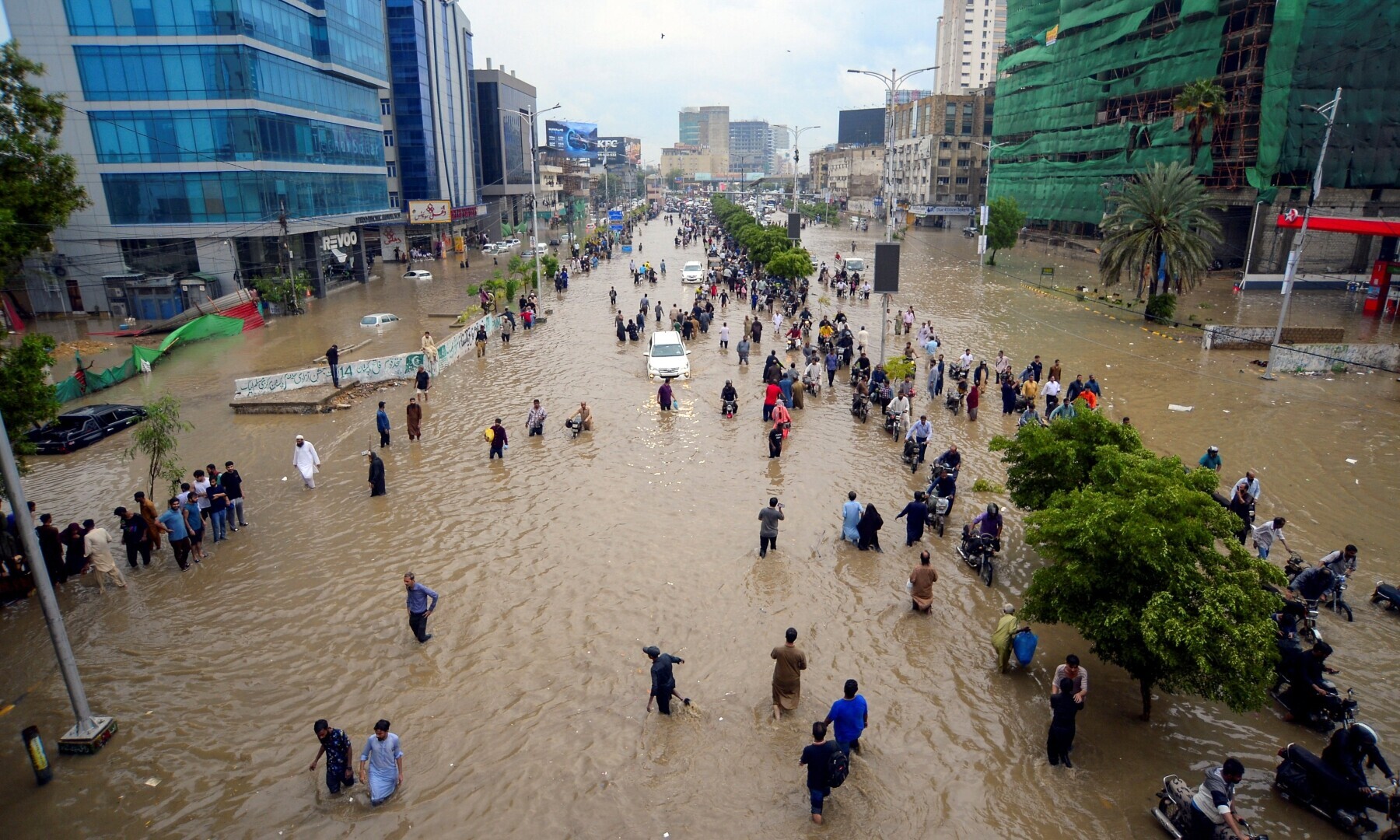 People wade through a flooded road after the monsoon rain in Karachi on August 19, 2025. — Reuters/Imran Ali